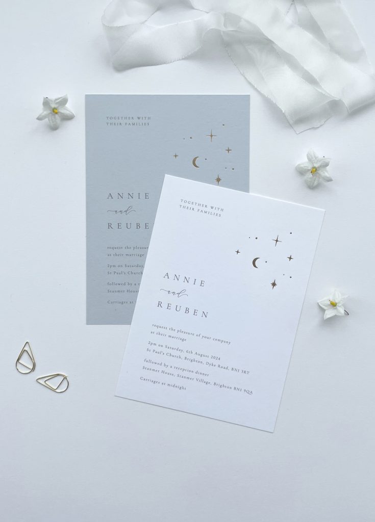 Gold foil celestial moon and stars luxury wedding invitation with a celestail design in gold foil in the corner of the invite and minimalist type on pale blue or white card