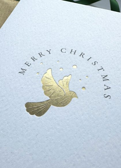 Luxury gold foil dove Christmas card symbolising peace and joy, flat lay with festive details and grey envelope