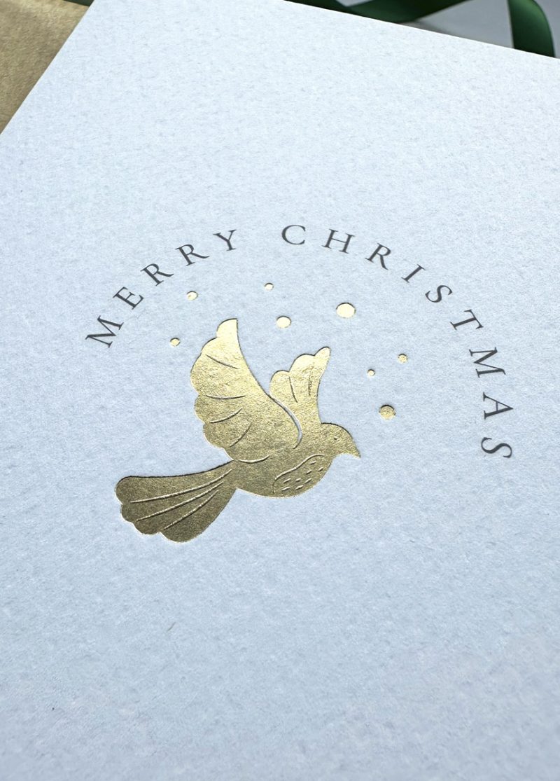 Luxury gold foil dove Christmas card symbolising peace and joy, flat lay with festive details and grey envelope