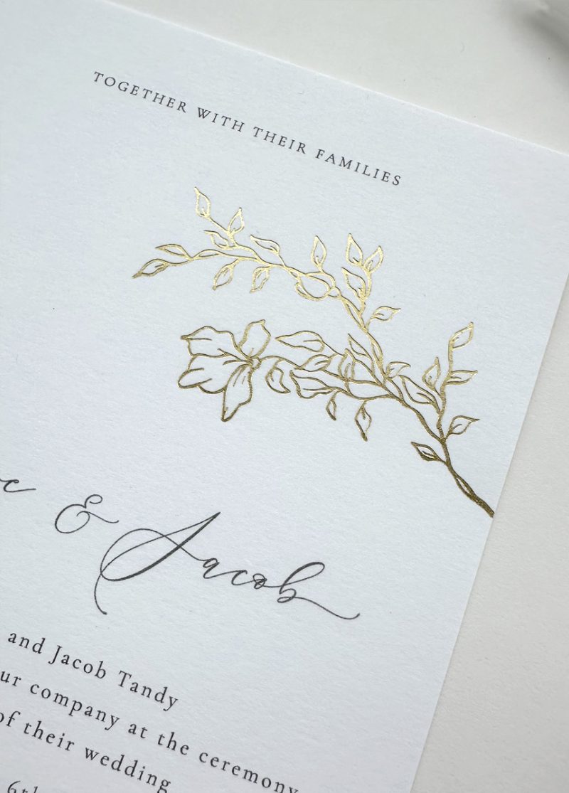 Modern botanical wedding invitation featuring gold branch illustration and floral envelope liner, elegant design.