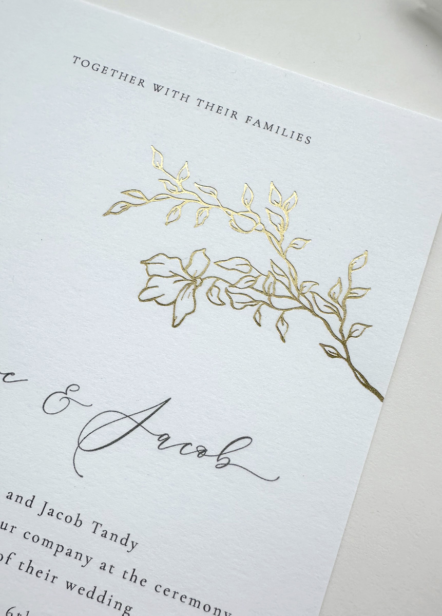Modern botanical wedding invitation featuring gold branch illustration and floral envelope liner, elegant design.