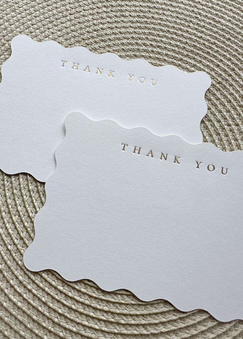 close up of elegant scalloped edge wedding thank you cards with gold foil