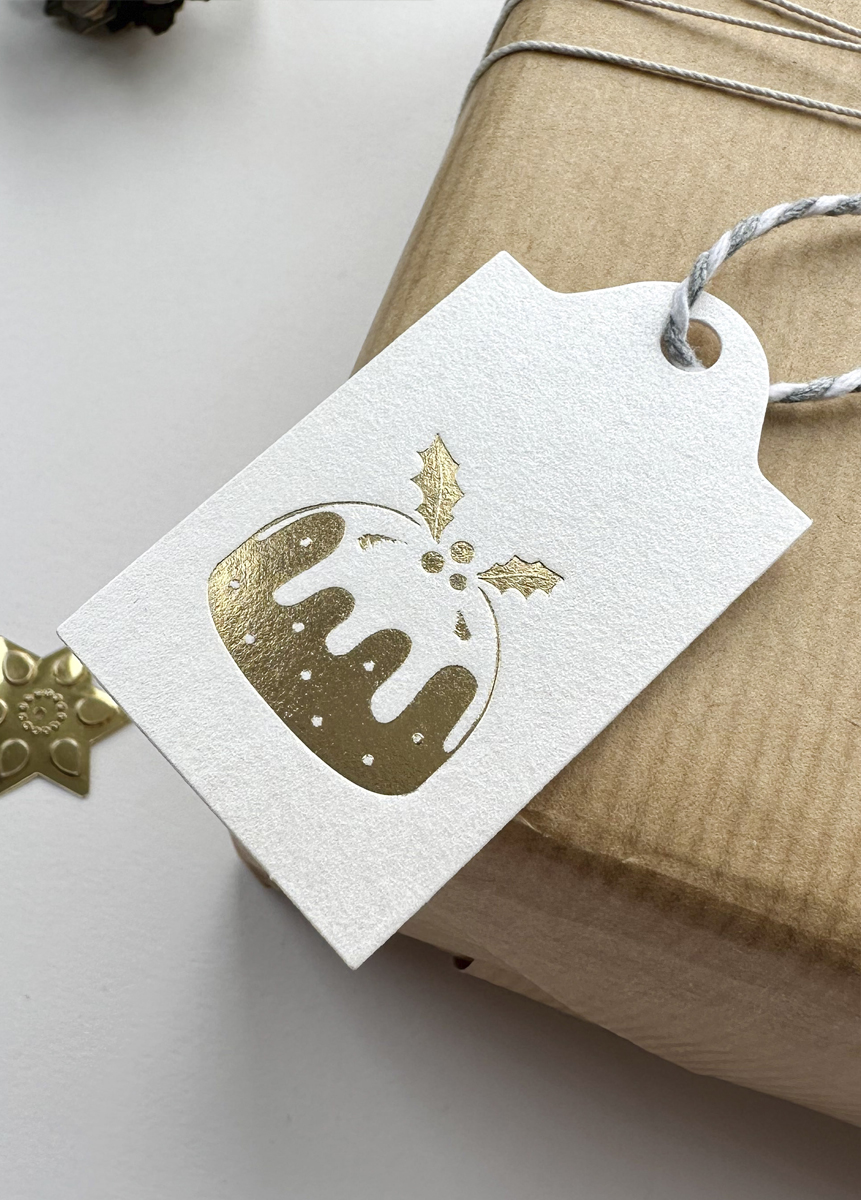 Minimalist Christmas pudding gift tag with gold foil detail, luxury holiday wrapping accessory.