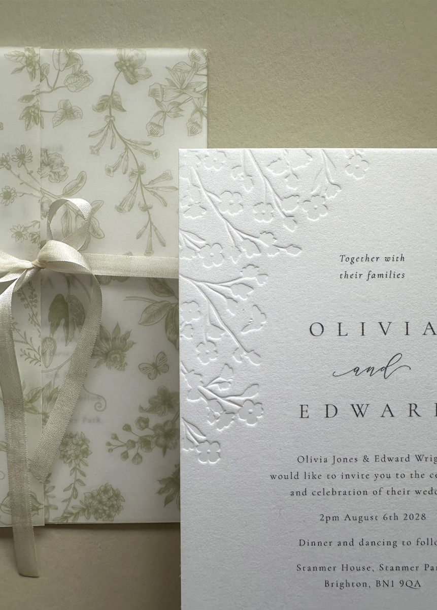 Embossed floral wedding invitation on premium cotton card paired with a sage green envelope and coordinating floral liner.