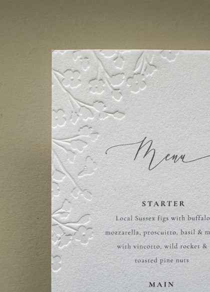 Floral embossed wedding menu card on premium cotton card coordinating with luxury wedding stationery.