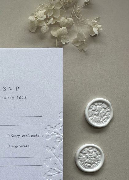 Luxury floral wedding wax seal securing a vellum wrap around a floral embossed wedding invitation suite.