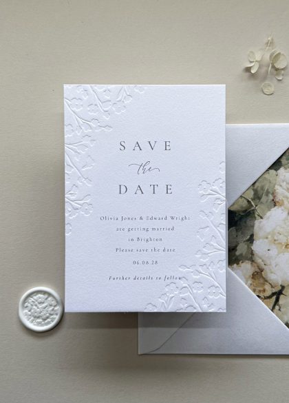 Luxury floral embossed Save the Date card printed on premium white cotton card with elegant raised botanical detailing for a timeless wedding announcement.