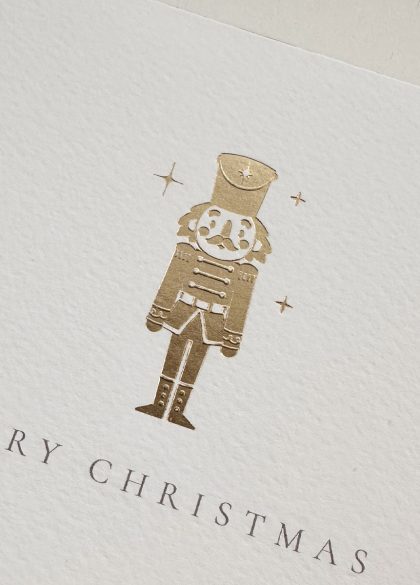 Close-up of the gold foil nutcracker illustration on a luxury Christmas greeting card.